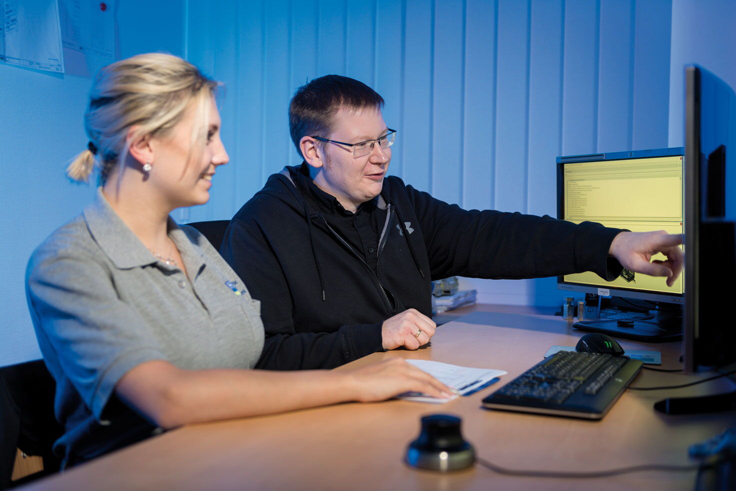 Frau und Mann beraten vor 3 Computerdisplays